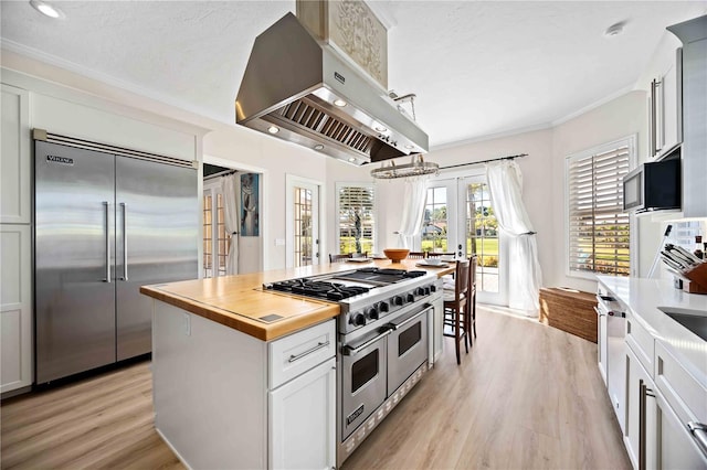 kitchen with white cabinetry, french doors, island exhaust hood, pendant lighting, and high end appliances