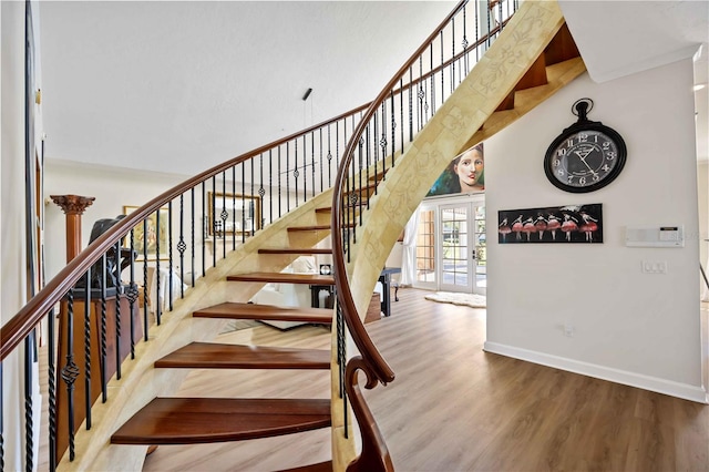 stairway with hardwood / wood-style floors and french doors