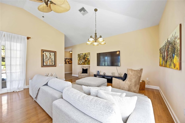 living room with vaulted ceiling, a fireplace, ceiling fan with notable chandelier, and light wood-type flooring