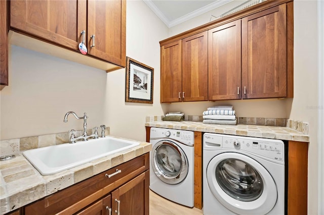 laundry area featuring cabinets, crown molding, sink, light hardwood / wood-style flooring, and washer and dryer