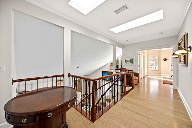 hall with light hardwood / wood-style floors, crown molding, and a skylight