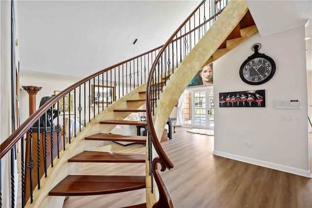 stairs with hardwood / wood-style floors, french doors, and a high ceiling