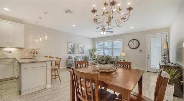 dining area featuring light hardwood / wood-style flooring, ceiling fan with notable chandelier, and sink