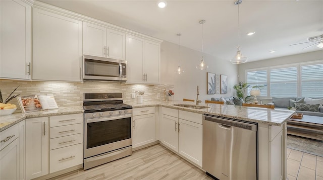 kitchen with white cabinetry, sink, stainless steel appliances, kitchen peninsula, and decorative light fixtures