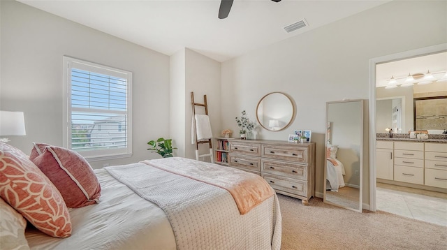 bedroom with ceiling fan, light colored carpet, and ensuite bathroom