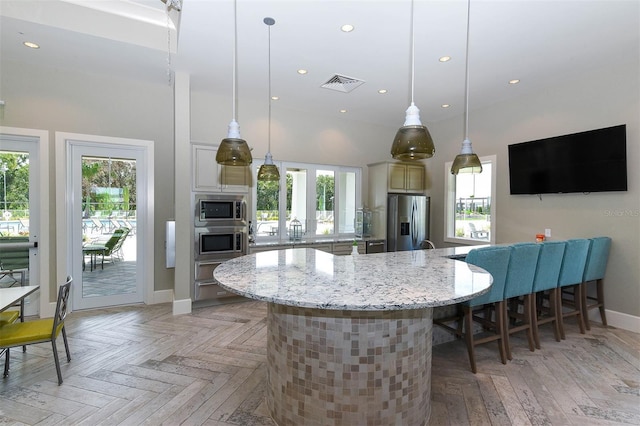 kitchen with hanging light fixtures, a breakfast bar area, a large island, light stone counters, and stainless steel appliances