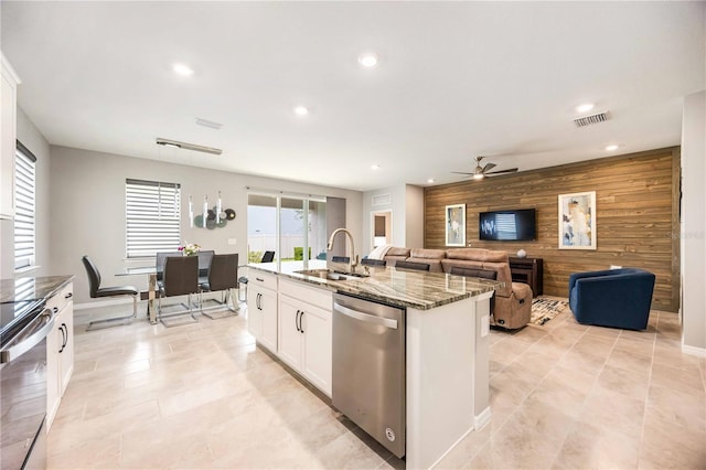 kitchen with sink, stainless steel appliances, dark stone counters, a center island with sink, and white cabinets