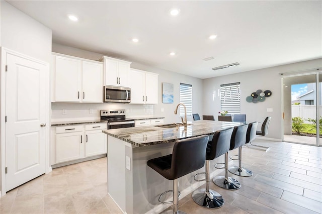 kitchen featuring stainless steel appliances, plenty of natural light, a center island with sink, and sink