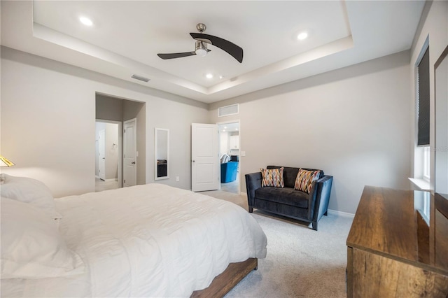 bedroom featuring light colored carpet, a raised ceiling, and ceiling fan