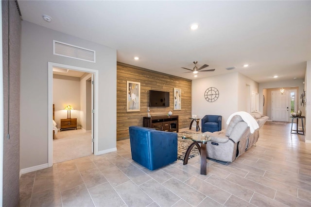 living room featuring ceiling fan and wood walls