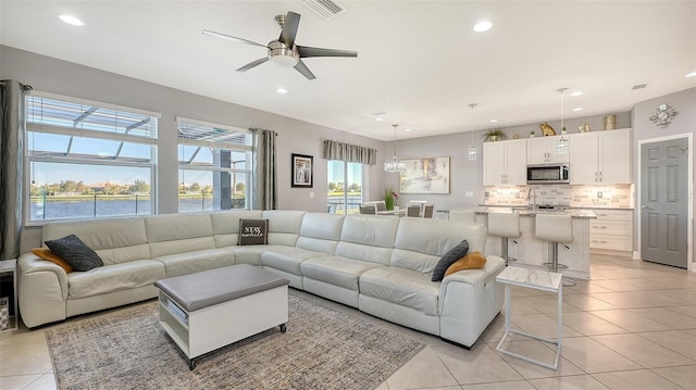 living room featuring light tile patterned floors, ceiling fan, and a healthy amount of sunlight