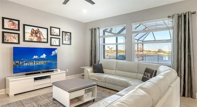 living room featuring a water view, ceiling fan, and light tile patterned floors