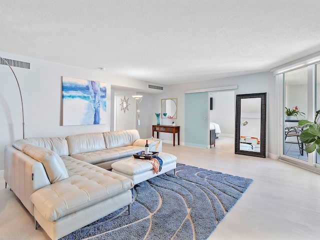 living room with light wood-style flooring, visible vents, and a textured ceiling