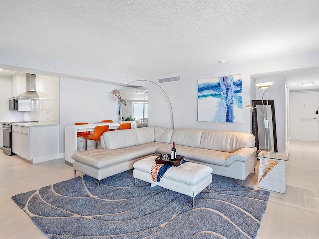 living room with light wood-style floors, visible vents, and a textured ceiling