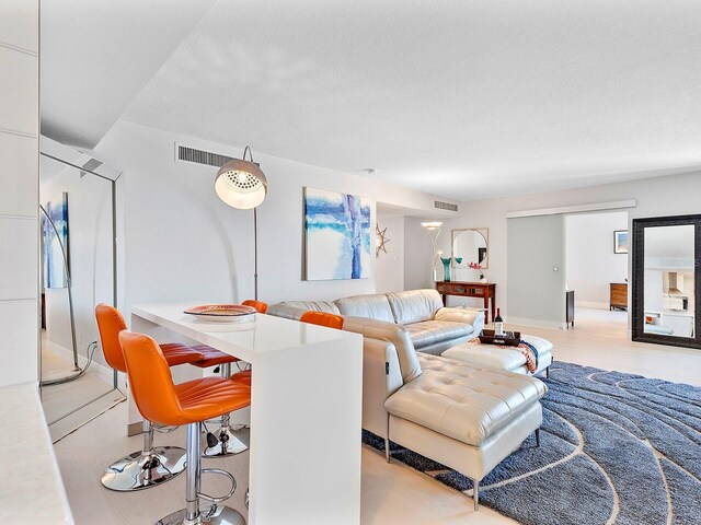 living room with light wood-style floors, visible vents, and a textured ceiling