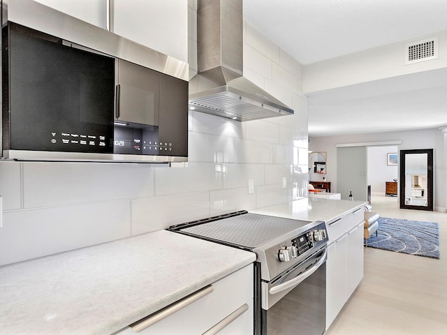 kitchen featuring visible vents, light countertops, decorative backsplash, appliances with stainless steel finishes, and wall chimney exhaust hood