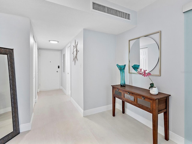 hall featuring visible vents, light wood-type flooring, and baseboards