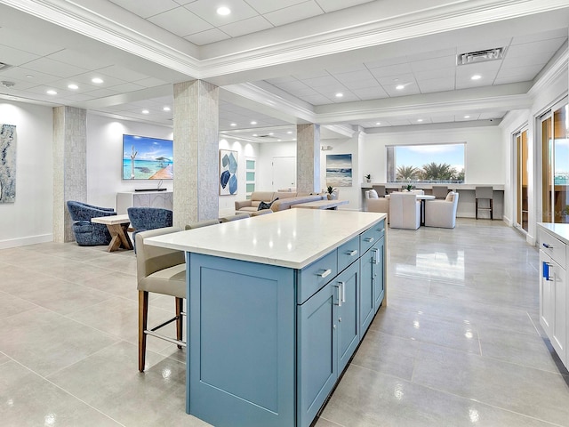 kitchen with a kitchen bar, visible vents, blue cabinetry, a kitchen island, and open floor plan