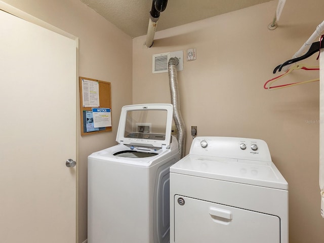 laundry area with laundry area, visible vents, and washer and clothes dryer