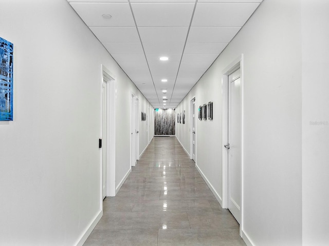 hallway with a drop ceiling and baseboards