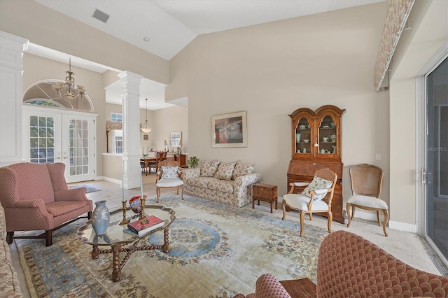 carpeted living room featuring french doors, high vaulted ceiling, ornate columns, and a notable chandelier