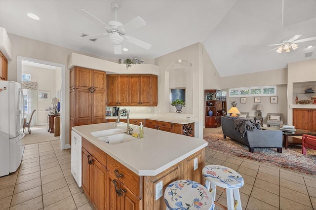 kitchen with sink, white fridge, a healthy amount of sunlight, and an island with sink