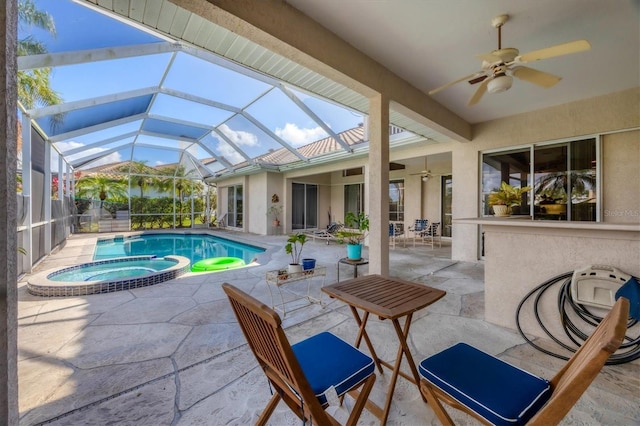 view of pool with glass enclosure, ceiling fan, a patio area, and an in ground hot tub