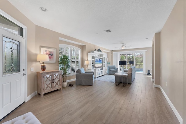 living room featuring a textured ceiling, light hardwood / wood-style flooring, and ceiling fan