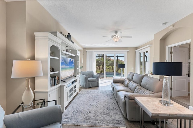 living room with hardwood / wood-style flooring, ceiling fan, and a textured ceiling