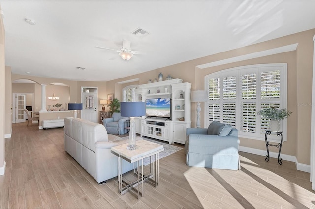 living room with decorative columns, ceiling fan, and light wood-type flooring