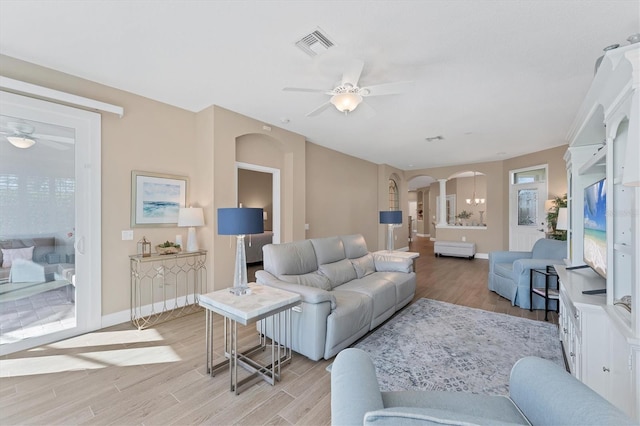 living room featuring ceiling fan with notable chandelier and light hardwood / wood-style floors