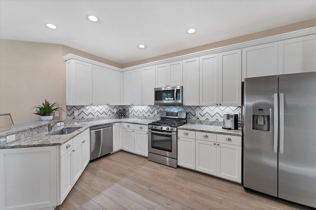 kitchen featuring white cabinetry, sink, stainless steel appliances, kitchen peninsula, and light hardwood / wood-style floors