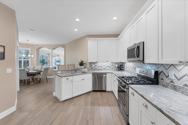 kitchen featuring white cabinets, hanging light fixtures, sink, appliances with stainless steel finishes, and light hardwood / wood-style floors