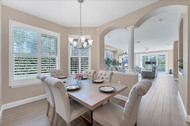 dining area with decorative columns, light hardwood / wood-style flooring, and ceiling fan with notable chandelier