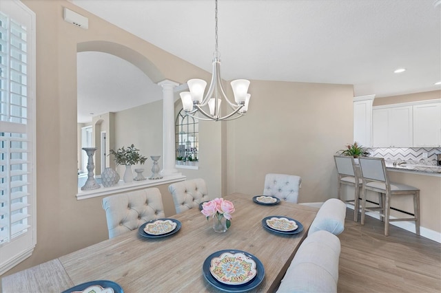 dining area featuring decorative columns, light hardwood / wood-style flooring, and an inviting chandelier