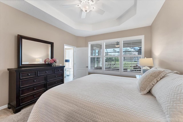 carpeted bedroom featuring a tray ceiling and ceiling fan