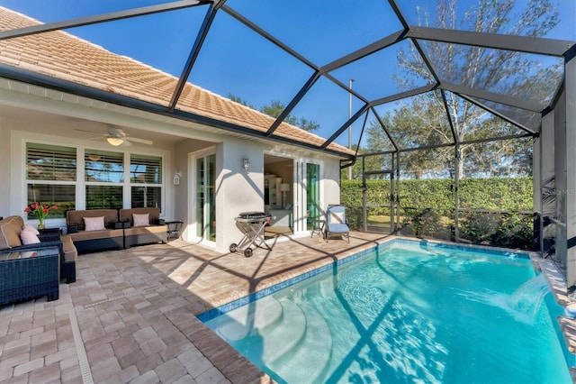 view of pool featuring glass enclosure, an outdoor hangout area, pool water feature, ceiling fan, and a patio area