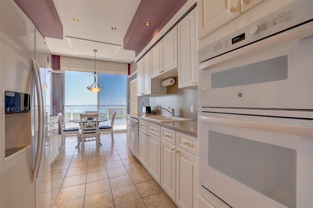 kitchen with stainless steel refrigerator with ice dispenser, white double oven, sink, pendant lighting, and white cabinets