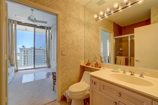 bathroom featuring ceiling fan, vanity, a shower with shower door, and toilet