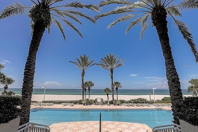 view of swimming pool featuring a water view and a beach view