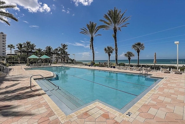 view of swimming pool featuring a patio area and a water view