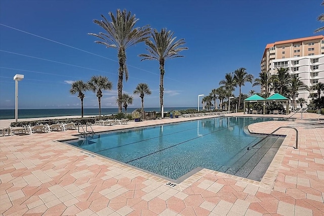 view of swimming pool with a patio area and a water view