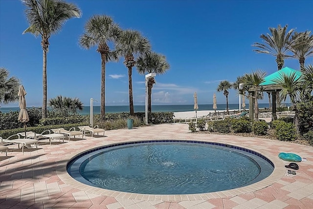 view of swimming pool featuring a patio and a water view