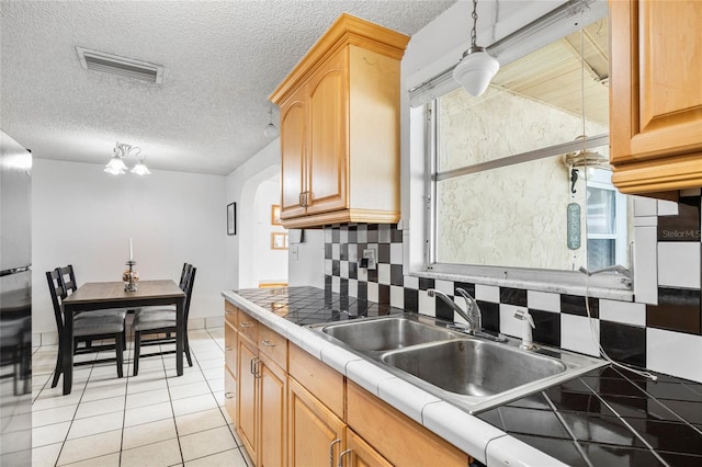 kitchen with pendant lighting, backsplash, sink, tile counters, and light tile patterned flooring