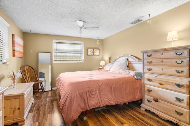 bedroom featuring ceiling fan, dark hardwood / wood-style flooring, and a textured ceiling