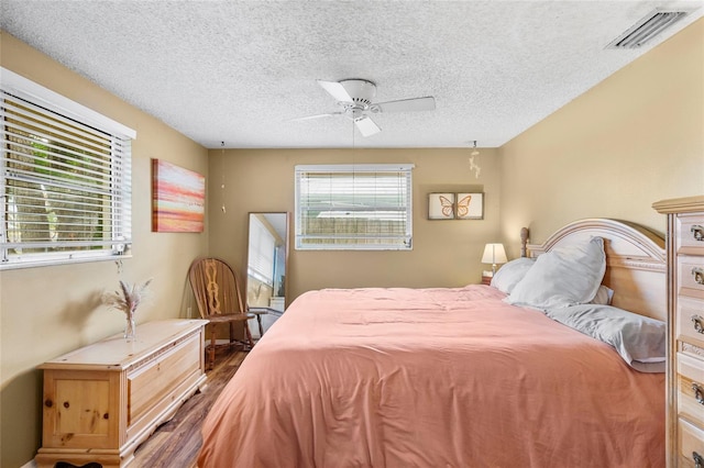 bedroom featuring ceiling fan, hardwood / wood-style floors, and a textured ceiling