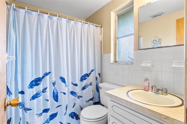 bathroom featuring a shower with curtain, a textured ceiling, toilet, vanity, and tile walls