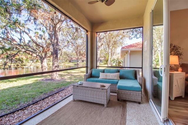 sunroom with ceiling fan and a water view