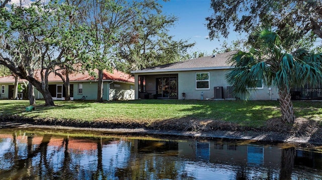 rear view of house with a water view and a yard