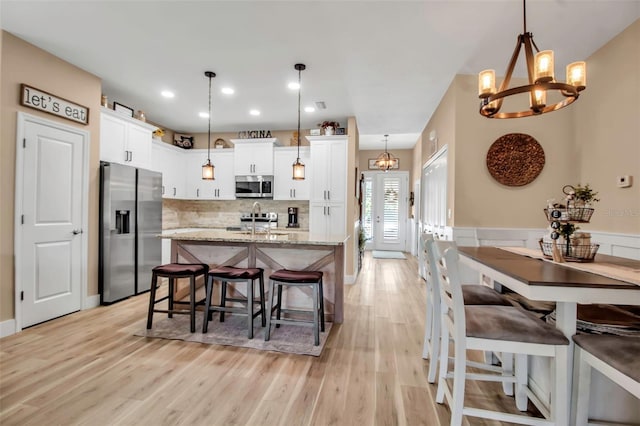 kitchen with a notable chandelier, light stone countertops, white cabinetry, hanging light fixtures, and stainless steel appliances